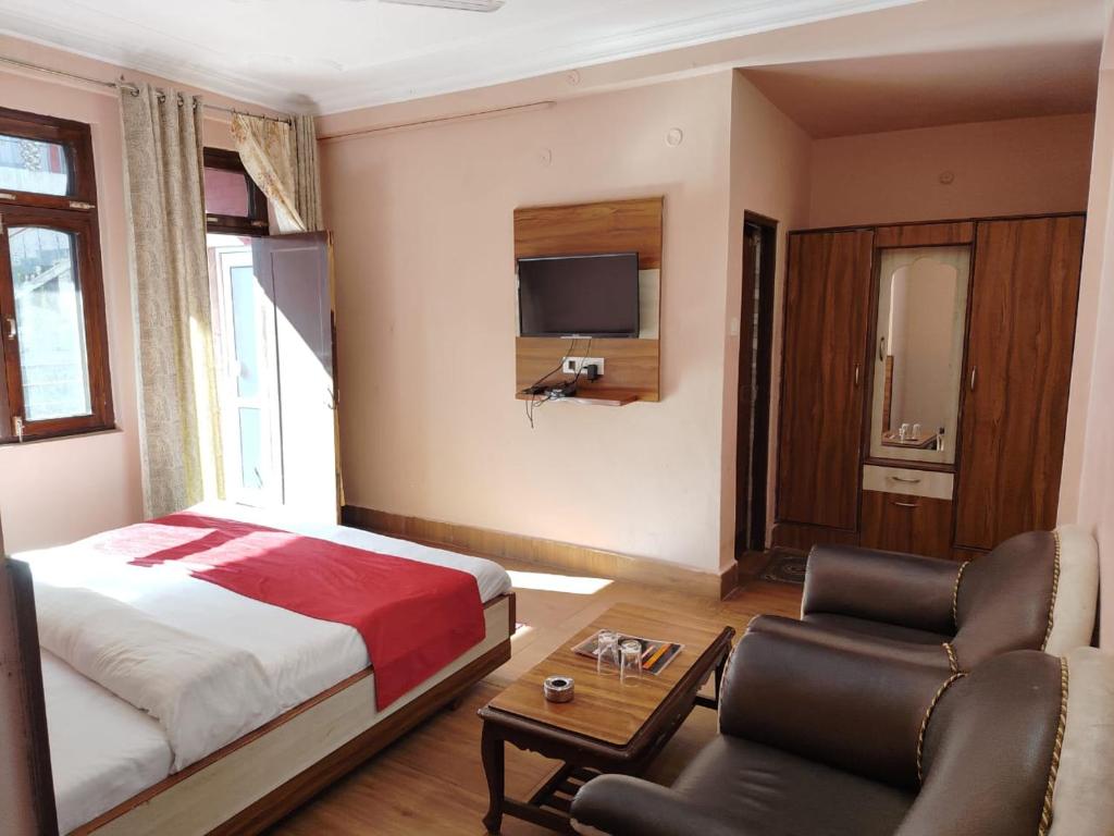 Un dormitorio con una cama, un sofá y un televisor. en Varuni Gd Hotel Mcleodganj, en McLeod Ganj