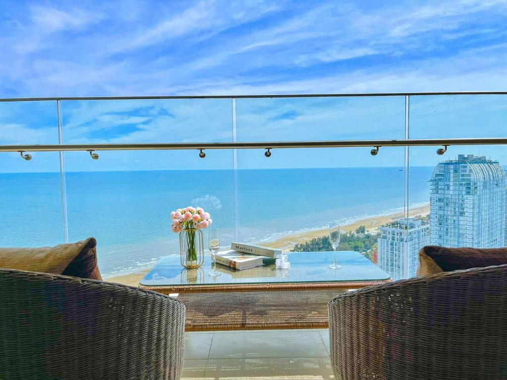 uma varanda de vidro com uma mesa e vista para a praia em The Song Apartment 5 Stars Vung Tau - Căn Hộ Du Lịch Cạnh Biển - Chappy's Homestay em Vung Tau