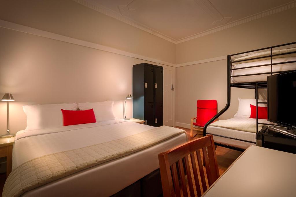 a bedroom with two beds and a desk and a television at Como Court Budget Accommodation in Melbourne