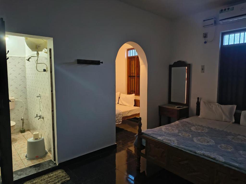 a bedroom with a bed and a bathroom with a mirror at Yali Homestay in Kuilapayam