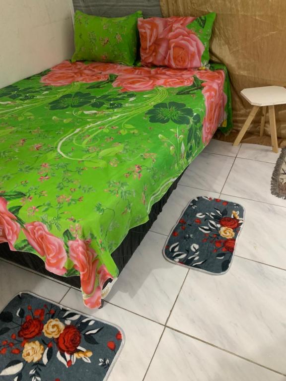 ein Schlafzimmer mit einem grünen Bett und zwei Matten auf dem Boden in der Unterkunft Kitnet Dream House 4 in Bayeux