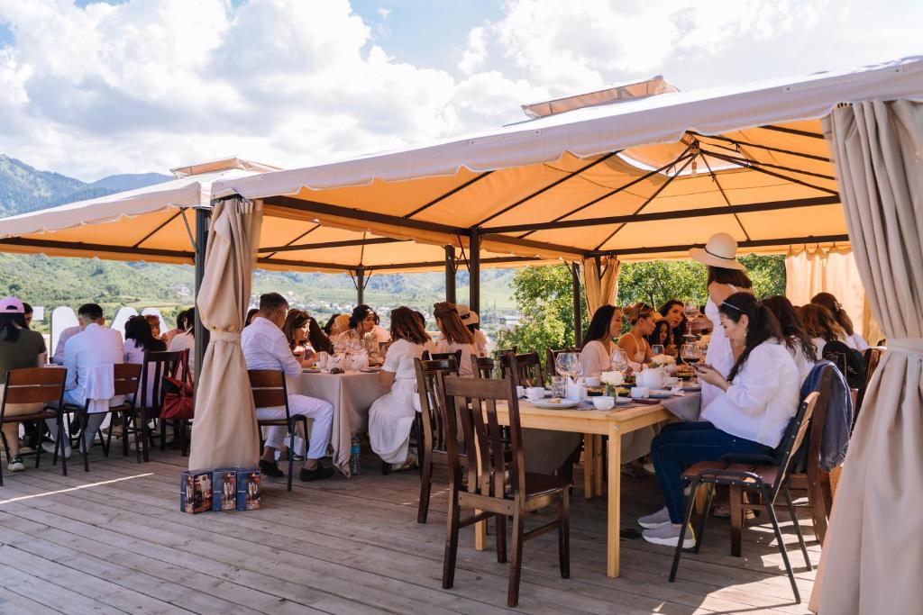 a group of people sitting at tables under umbrellas at Гора Глэмпинг in Besqaynar