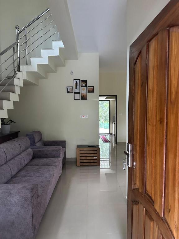 a living room with a couch and a staircase at Vathika Villa in Sultan Bathery