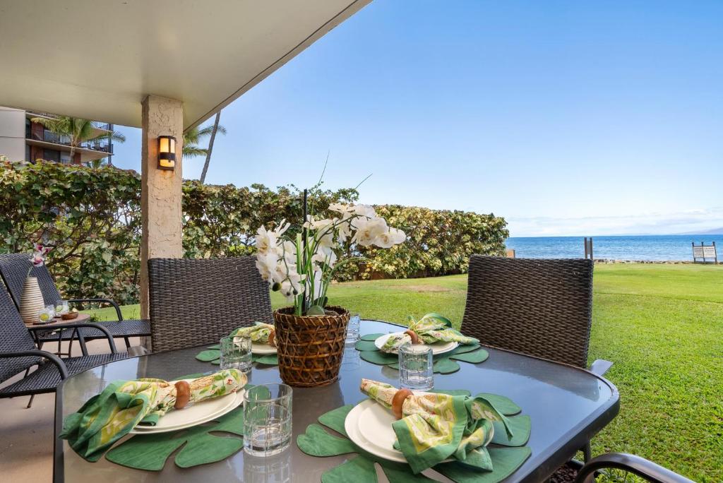 a table with plates of food on it with the ocean in the background at Papakea L101 · PK L101 Maui Ground-Floor Condo with Ocean Views in Honokowai