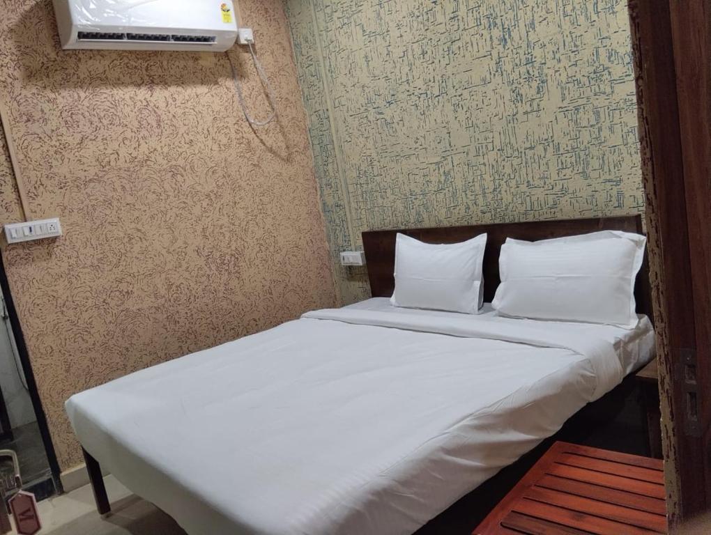 Una cama con sábanas blancas y almohadas en una habitación. en Hotel Vishnu Inn, en Rewa