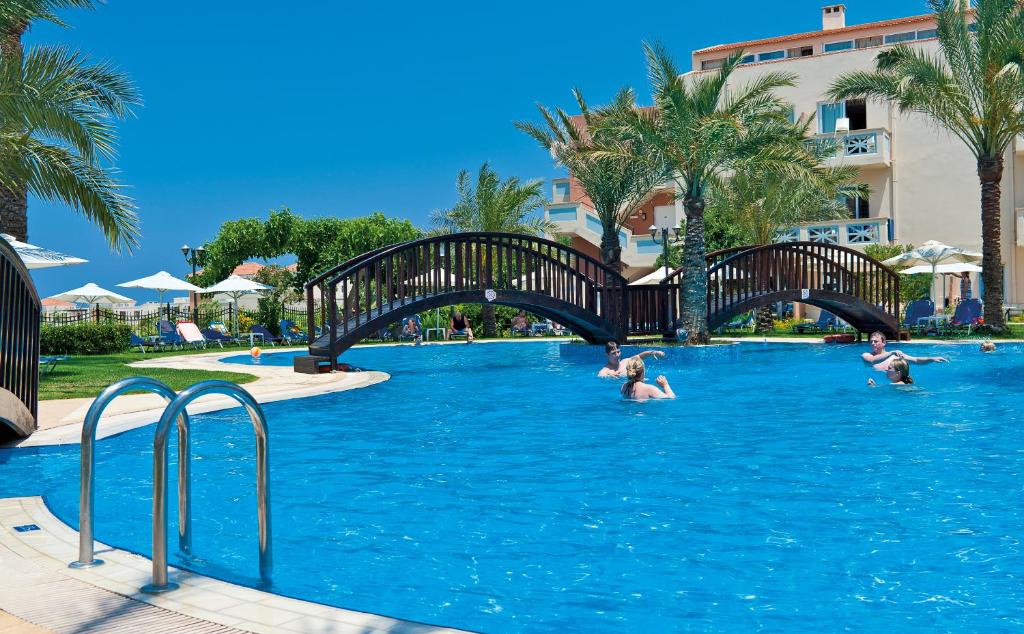 a group of people in a swimming pool with a bridge at Selini Suites & Waterpark in Kolymvari