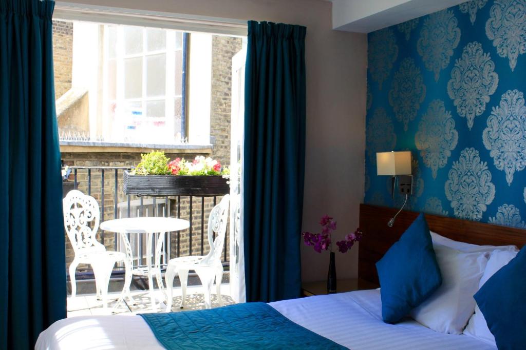 a bedroom with a bed and a balcony with a table and chairs at Sheriff Hotel in London