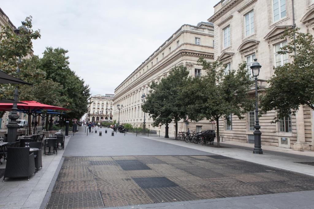 een stadsstraat met tafels, stoelen en gebouwen bij Grand Théâtre Bright Apartment in Bordeaux