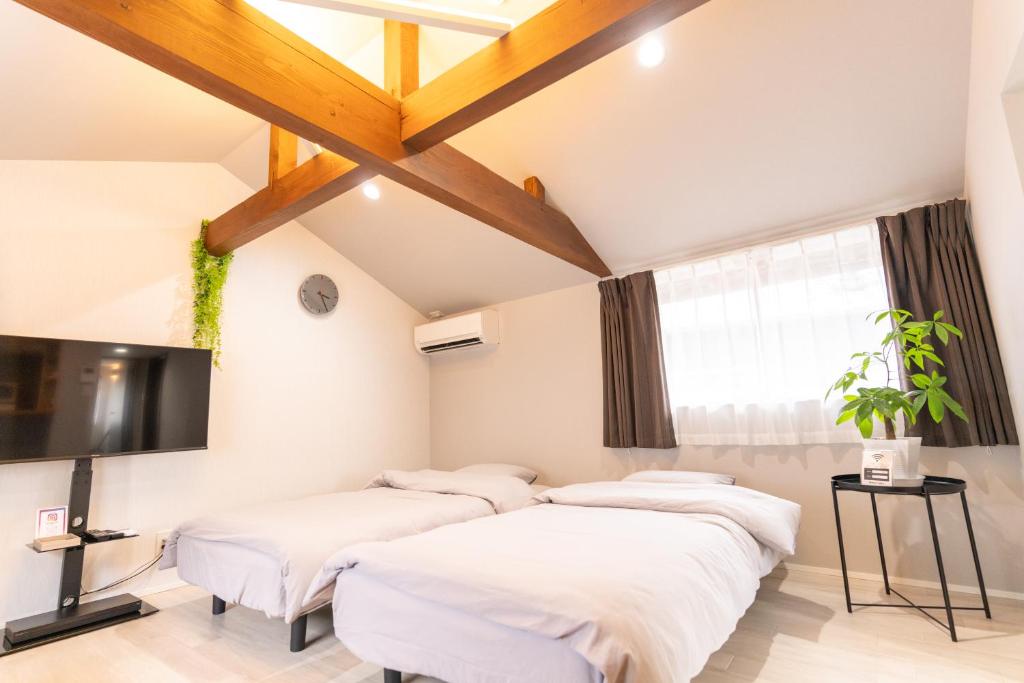 a room with four beds and a flat screen tv at Rino-Haku 02 in Anan