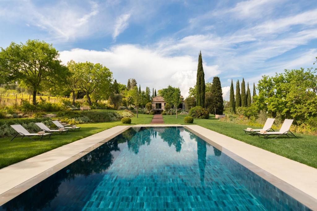 a swimming pool in a garden with lounge chairs at Godiluva in Palazzone
