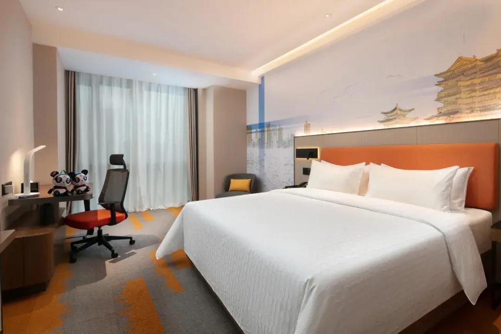 a hotel room with a large white bed and a desk at Hilton Garden Inn Nanchang Chaoyang Center in Nanchang