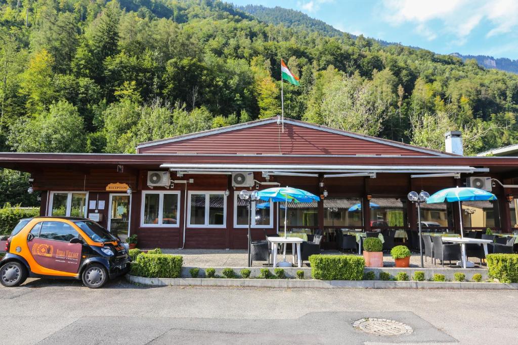 una piccola auto parcheggiata di fronte a un edificio di The River Village a Interlaken