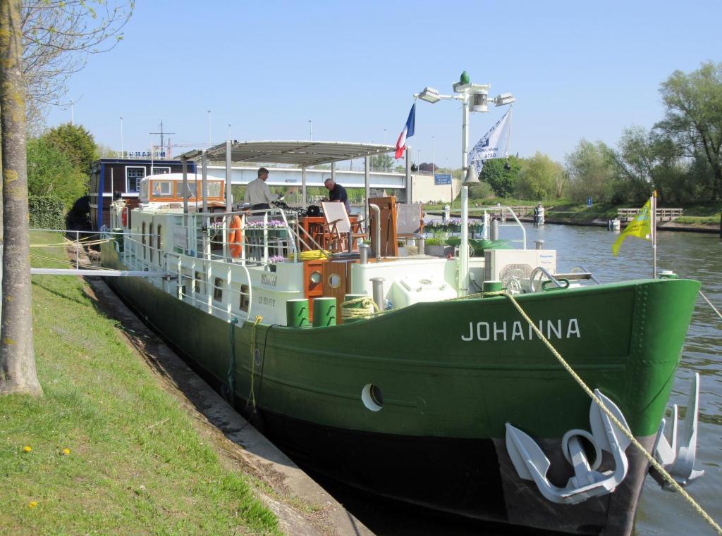 a green boat is docked in the water at B&B Barge Johanna in Bruges