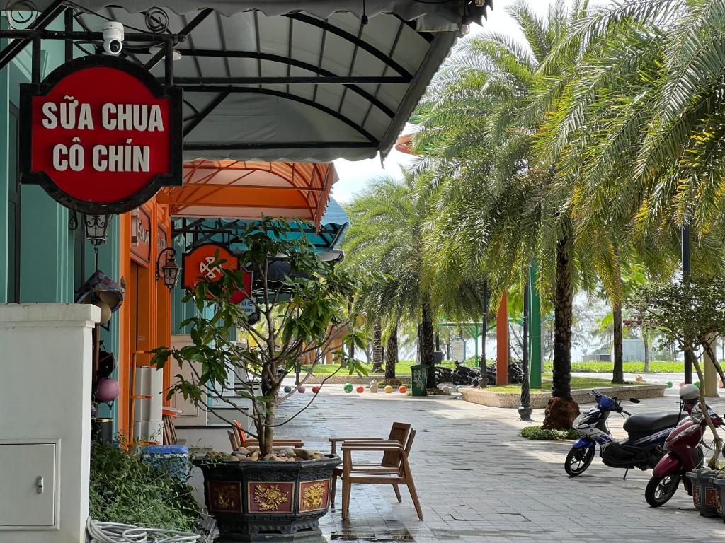 a sign for a restaurant with palm trees and scooters parked outside at Sua Chua in Phú Quốc