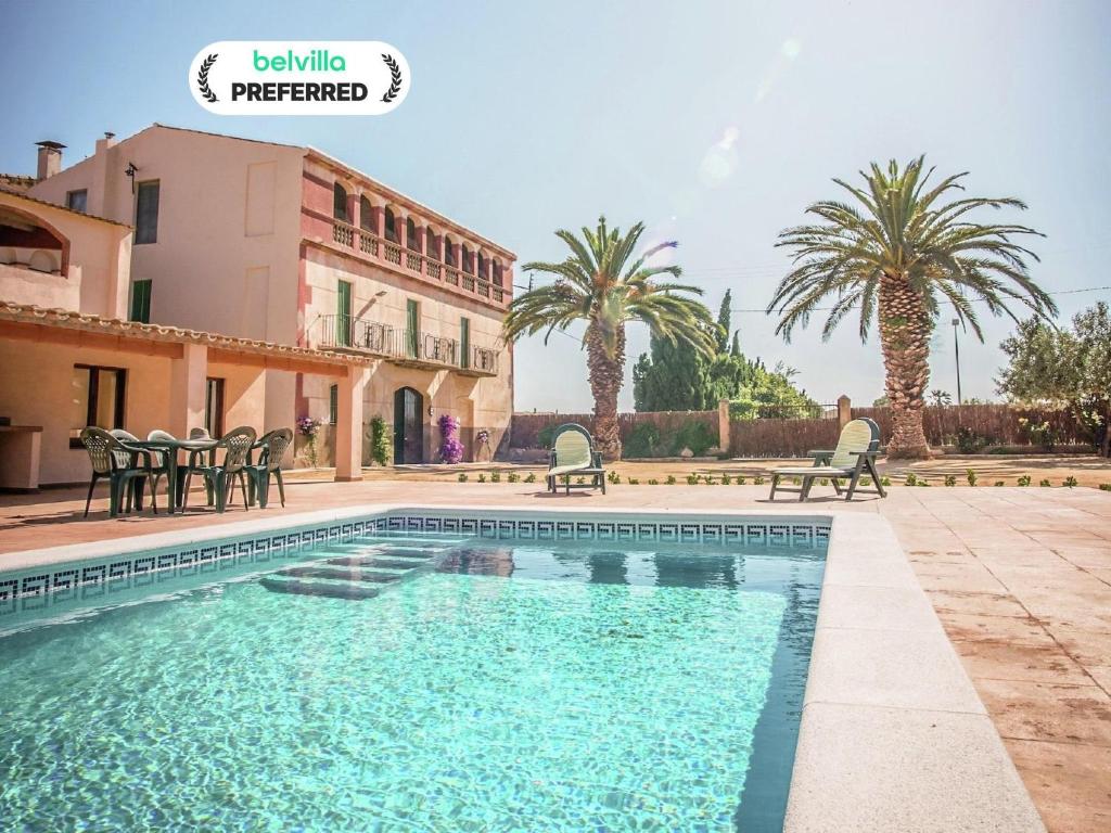 a swimming pool in front of a house with palm trees at Holiday Home in St Pere Pescador with Pool in Sant Pere Pescador