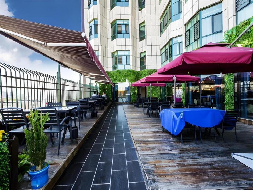 a patio with tables and chairs and umbrellas at Metropolo Hotel Yining Development Zone Hanma Building in Yining Airport