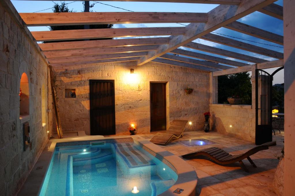 a patio with a swimming pool and a wooden pergola at Micele Holiday Houses in Locorotondo