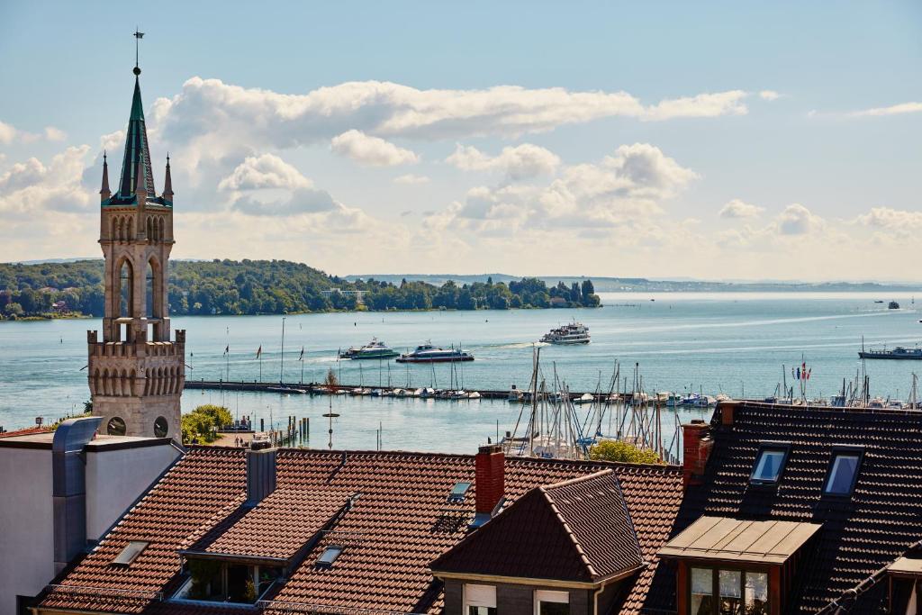 Blick auf eine Stadt mit einem Uhrturm und das Wasser in der Unterkunft Hotel Viva Sky in Konstanz