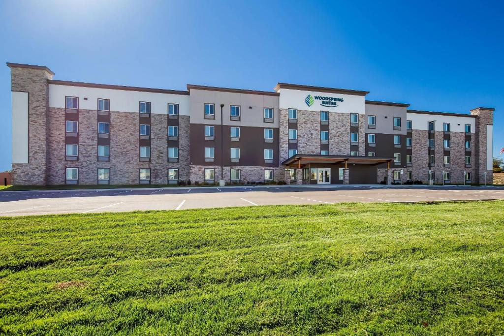 a large building with a grass field in front of it at WoodSpring Suites St Peters-OFallon in Saint Peters