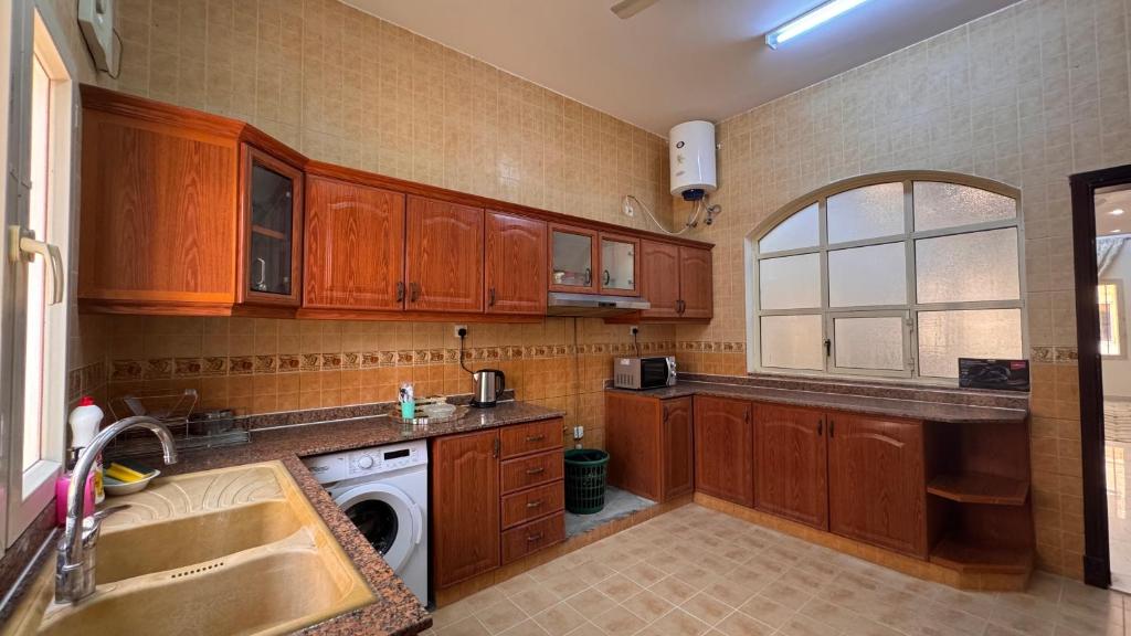 een keuken met houten kasten, een spoelbak en een vaatwasser bij Sultan Beach House in Muscat