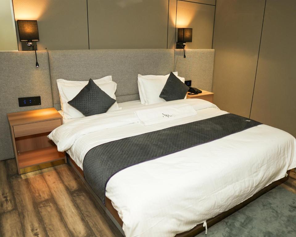 una cama blanca grande en una habitación de hotel en Hotel Aroma Inn, en Morādābād