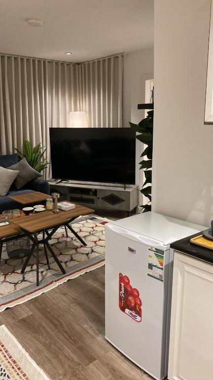 Una sala de estar con refrigerador y televisor. en شقة بغرفة وصالة, en Riad
