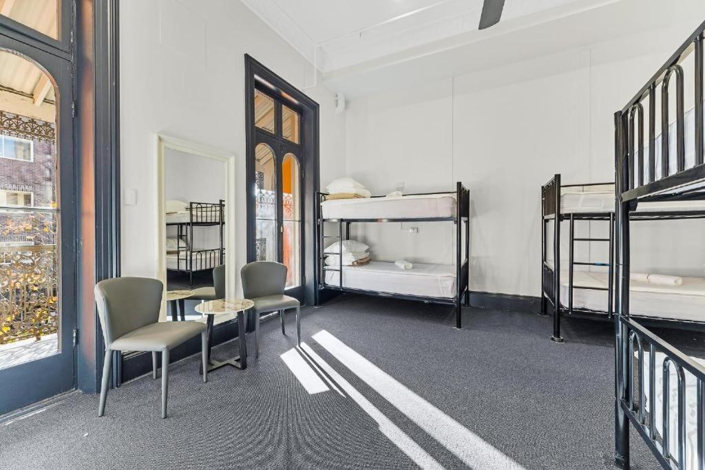 a room with bunk beds and a table and chairs at London Gate Backpackers Hotel in Sydney