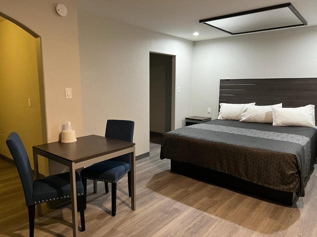 a bedroom with a bed and a table and chairs at Cloud 9 Inn - El Ciello Inn in Pico Rivera