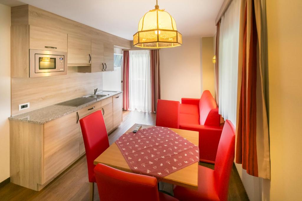 małą kuchnię ze stołem i czerwonymi krzesłami w obiekcie Apartments Diamant w mieście Ortisei