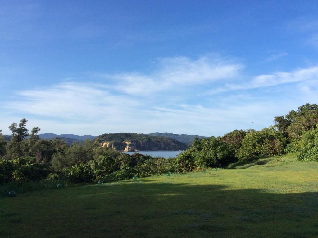 een groen veld met een meer op de achtergrond bij Mayagusuku Resort in Iriomote