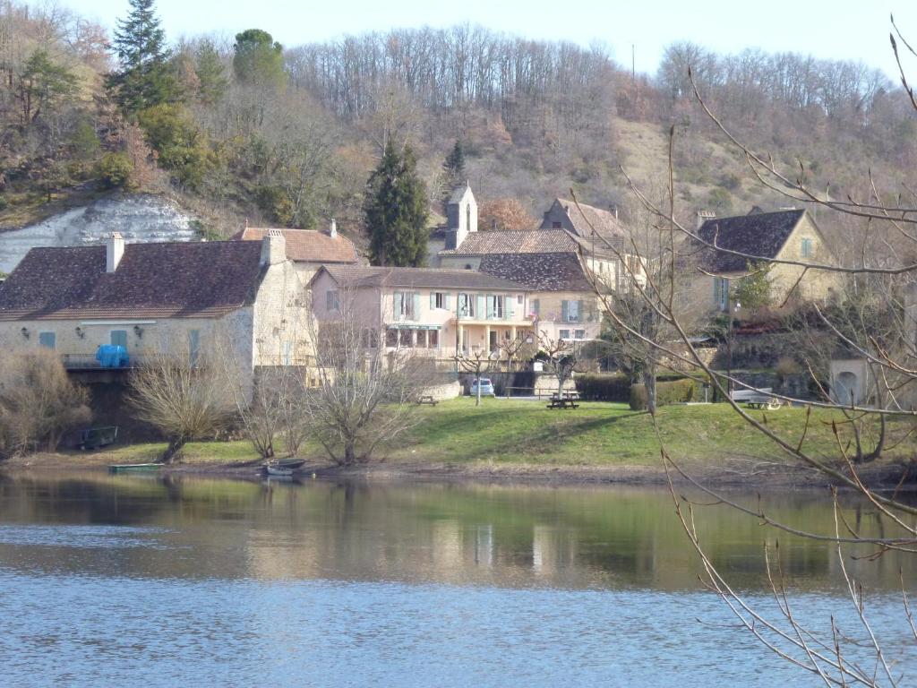 um grupo de casas numa colina junto a um rio em Hôtel-Restaurant Côté Rivage em Badefols-sur-Dordogne