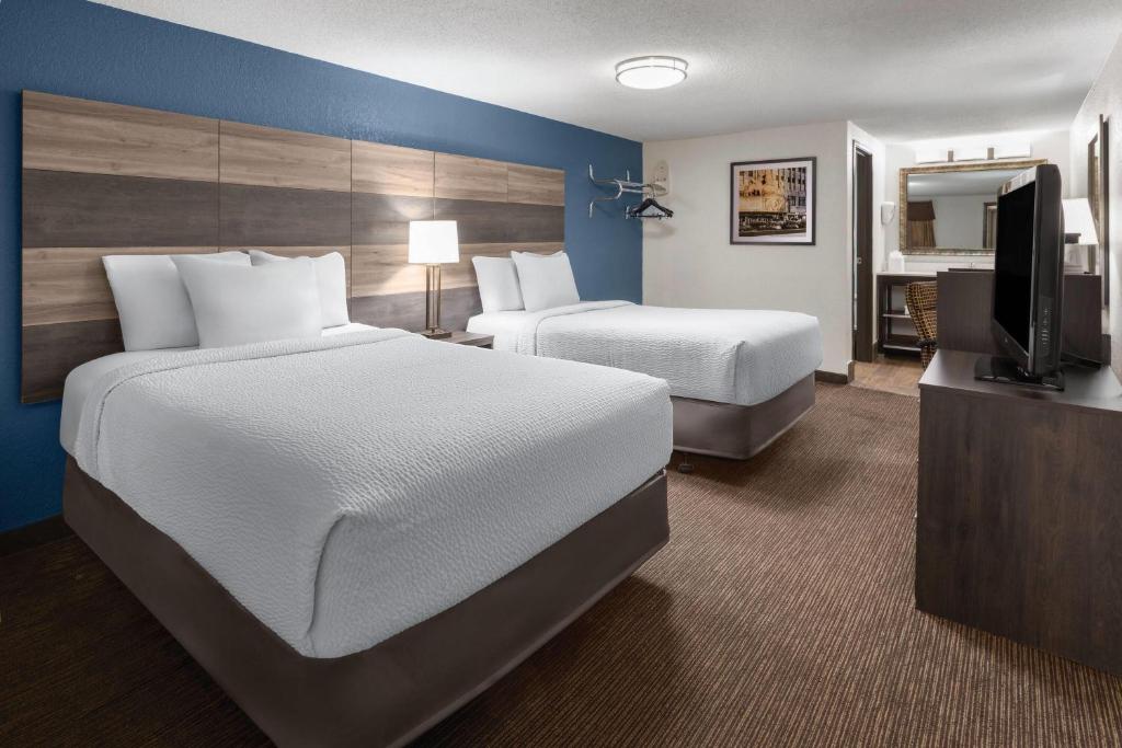 a hotel room with two beds and a flat screen tv at Baymont by Wyndham Downtown Detroit in Detroit