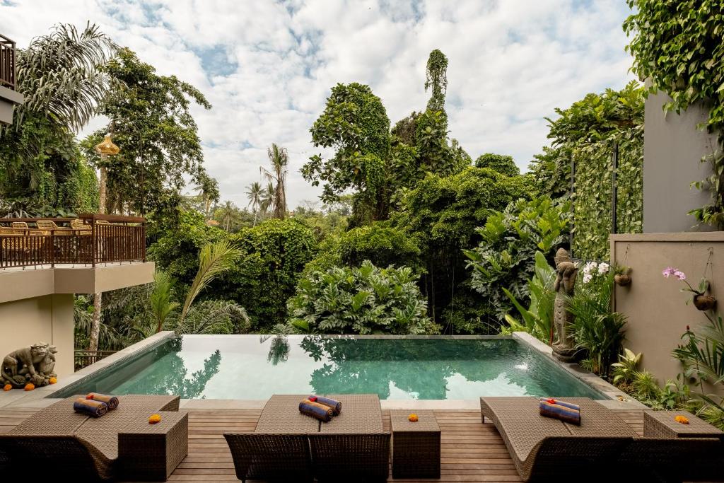 a swimming pool in the middle of a garden at Orchid Ubud Cottage in Ubud