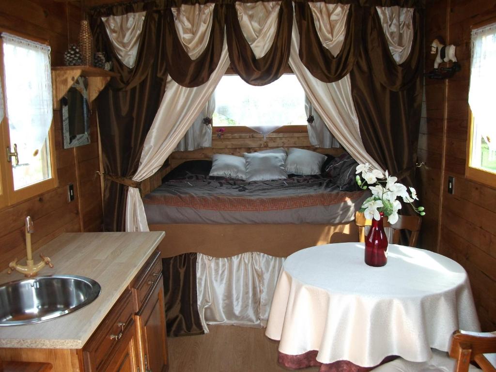 ein Schlafzimmer mit einem Tisch und einem Bett in einem Zimmer in der Unterkunft Les Roulottes des Songes de l'Authie in Boufflers