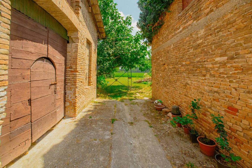 an alley with a brick wall and some potted plants at Ancient farmhouse 