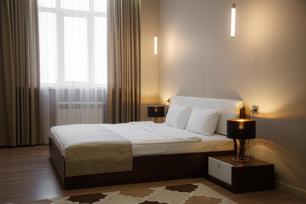 a bedroom with a large bed with a window at Baitau Hotel Aktobe in Aktobe