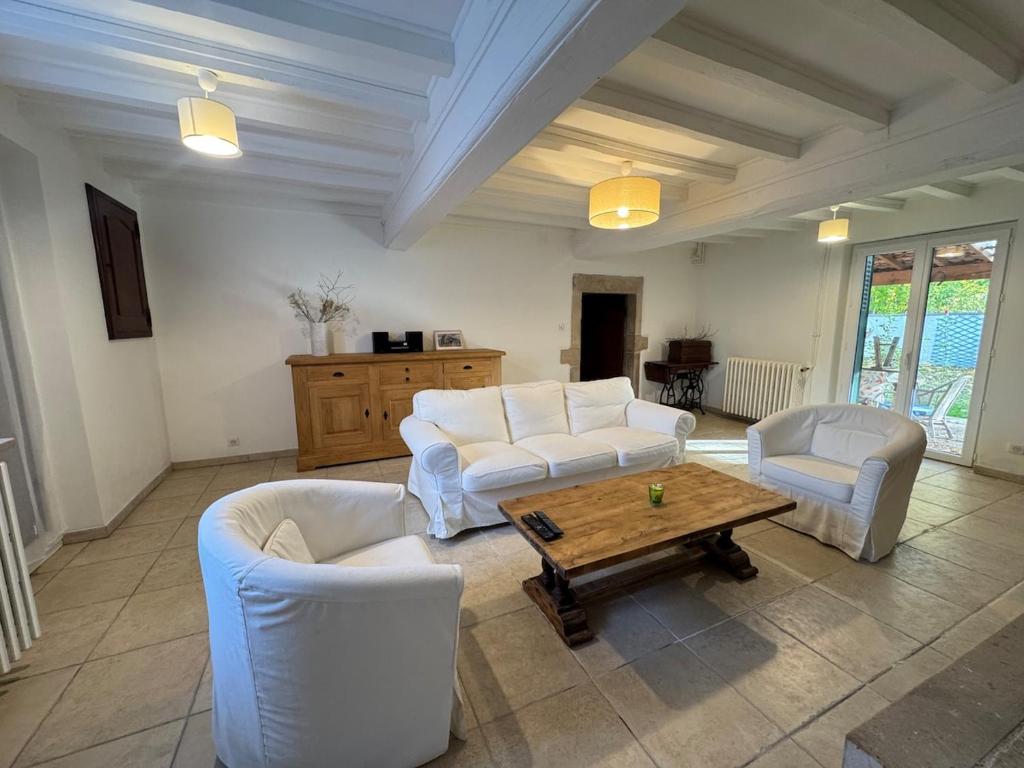 a living room with white couches and a wooden table at L'escapade Beaujolaise in La Chapelle-de-Guinchay