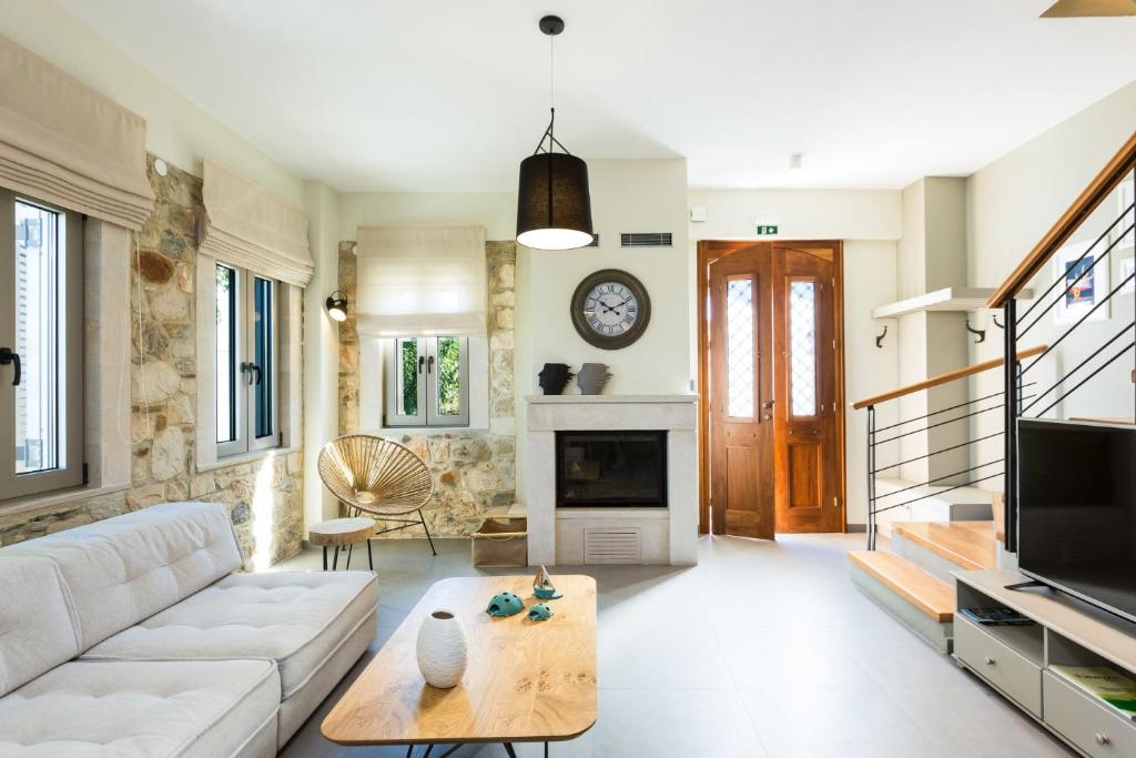 a living room with a white couch and a fireplace at Philoxenia Residences in Panormos Rethymno