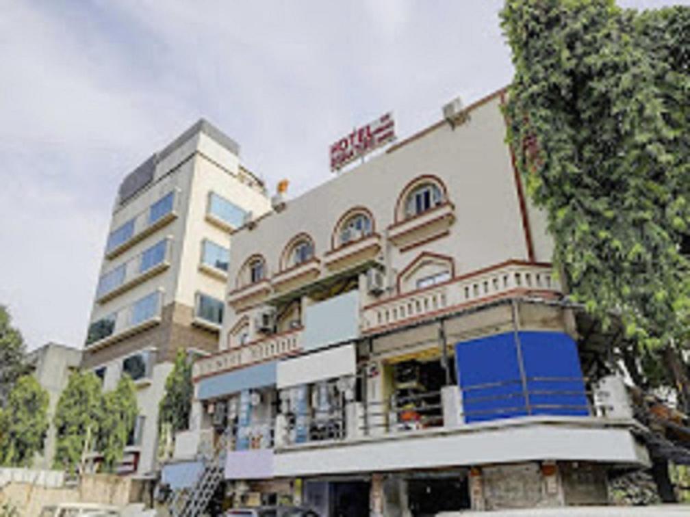 un gran edificio blanco con un gran árbol delante en Hotel Signature, en Ahmedabad