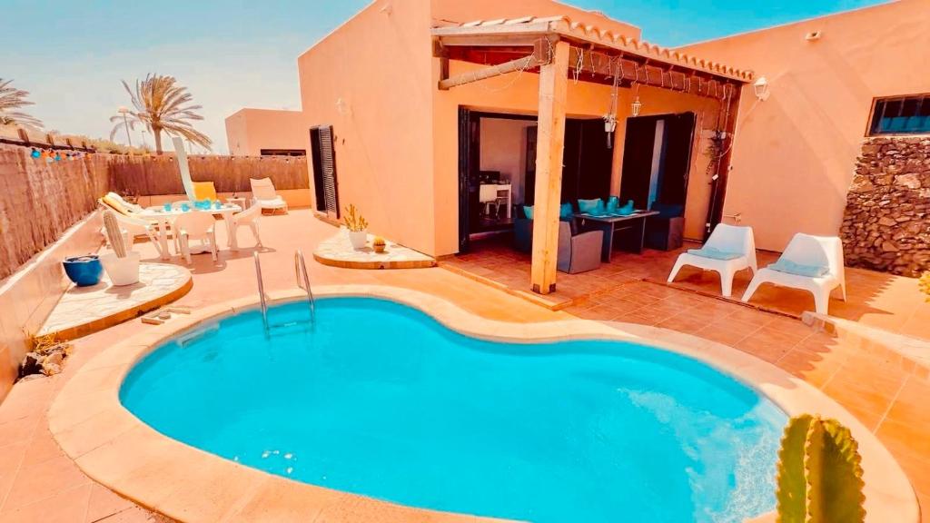 a swimming pool in a yard with a house at Dar Nur Villa Private pool, Barbecue and Solarium in La Oliva