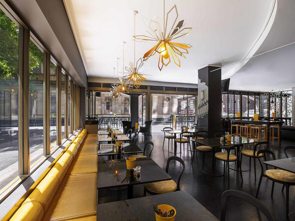 a restaurant with tables and chairs and windows at Mantra on Little Bourke Melbourne in Melbourne