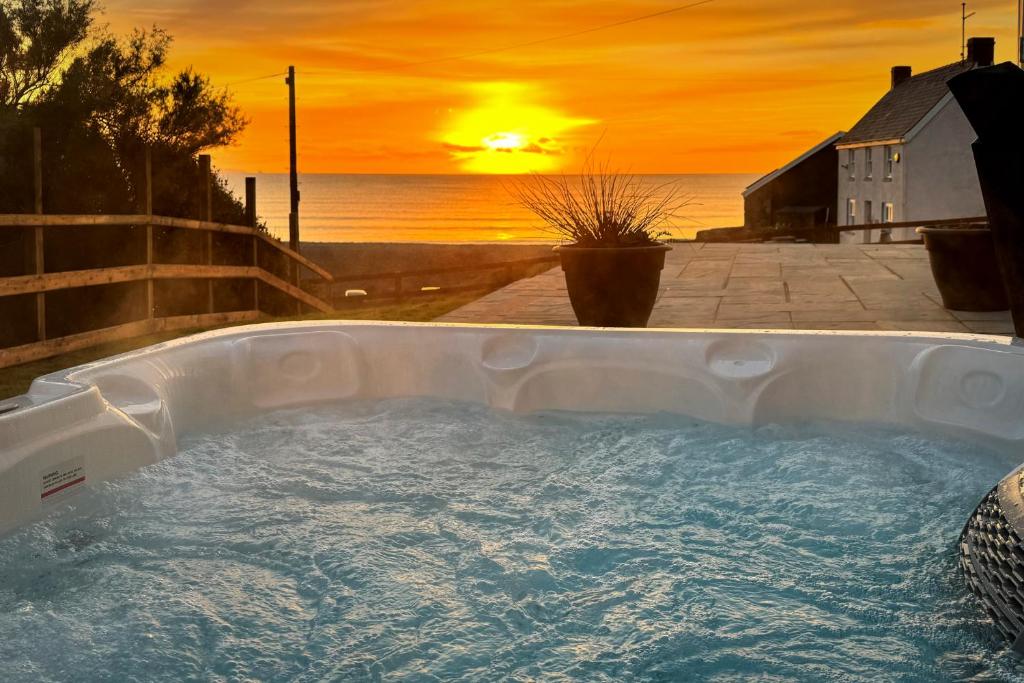einen Whirlpool mit Sonnenuntergang im Hintergrund in der Unterkunft Swn Y Don - Modern Luxury Steps from Newgale Beach Bliss for up to 10 People in Newgale
