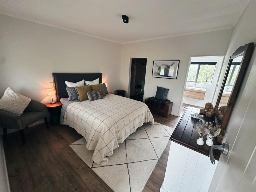 a bedroom with a bed and a chair and a window at Cariad Apartment in Alexandra