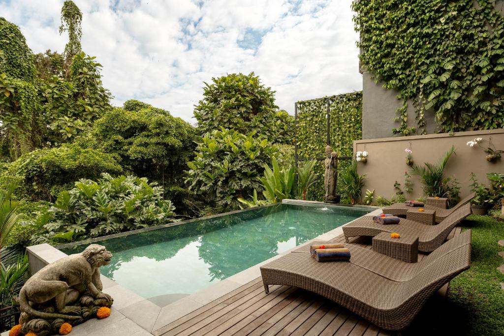 een tuin met een zwembad en een terras met een apenbeeld bij Orchid Ubud Cottage in Ubud