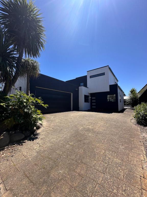 a black and white building with a garage at Modern Costal Escape-with Spa in Papamoa
