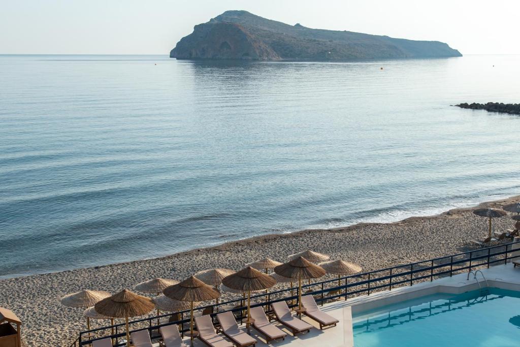 een strand met stoelen en parasols naast het water bij Hotel Haris on the beach in Agia Marina Nea Kydonias