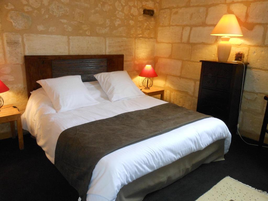 a bedroom with a large bed with two lamps at Les Logis du Roy in Saint-Émilion
