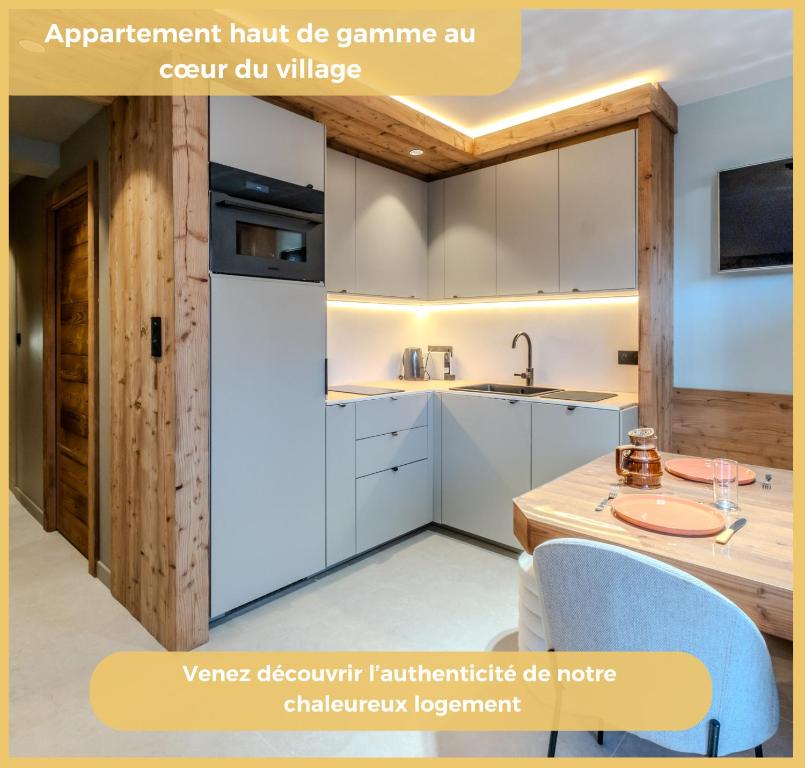 una cucina a pianta aperta con armadi bianchi e tavolo in legno di L'Élégance Alpine I Centre Les Gets a Les Gets