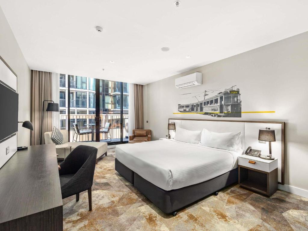a hotel room with a bed and a desk at Peppers Docklands in Melbourne