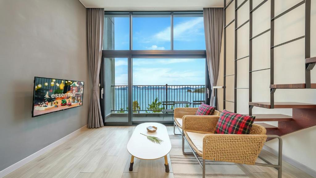 Una sala de estar con un sofá y sillas y una ventana grande. en Yeosu dasi bom pension, en Yeosu